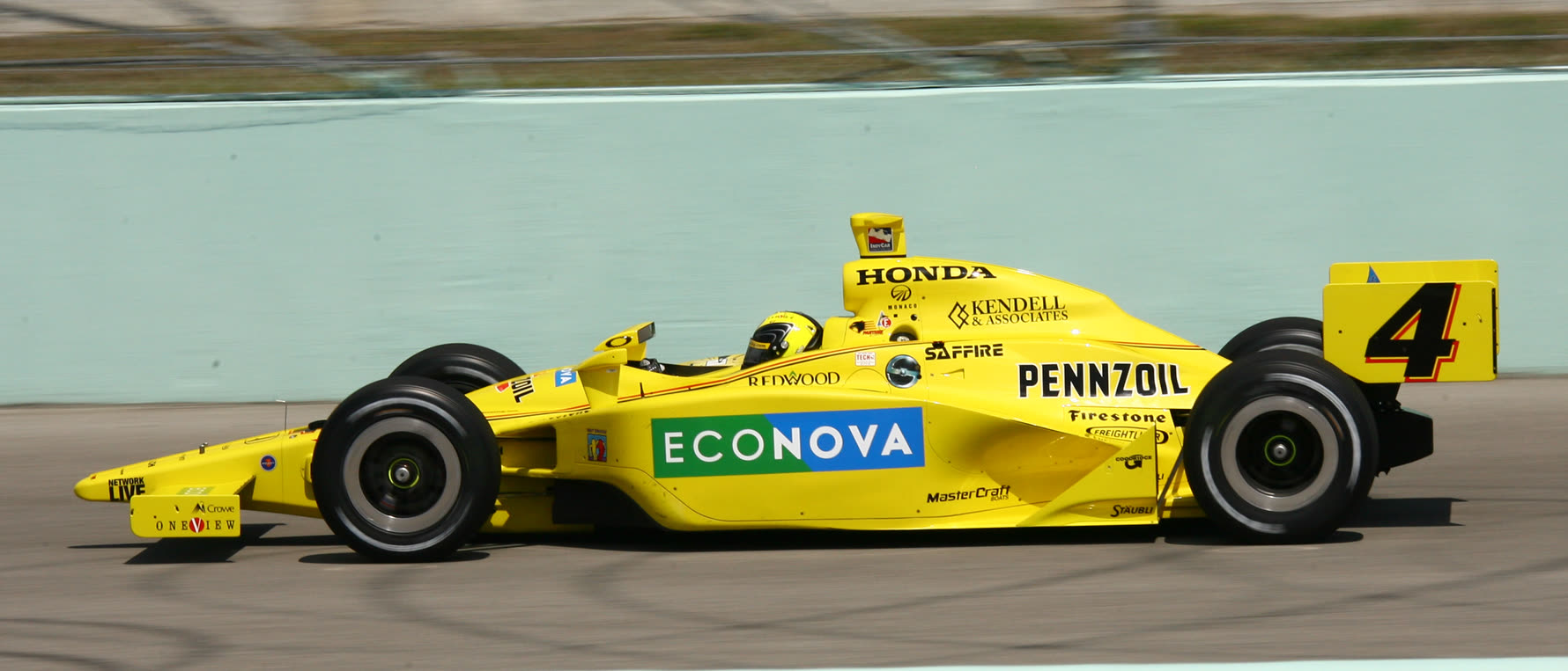 An IndyCar in Kendell & Associates livery at speed on track