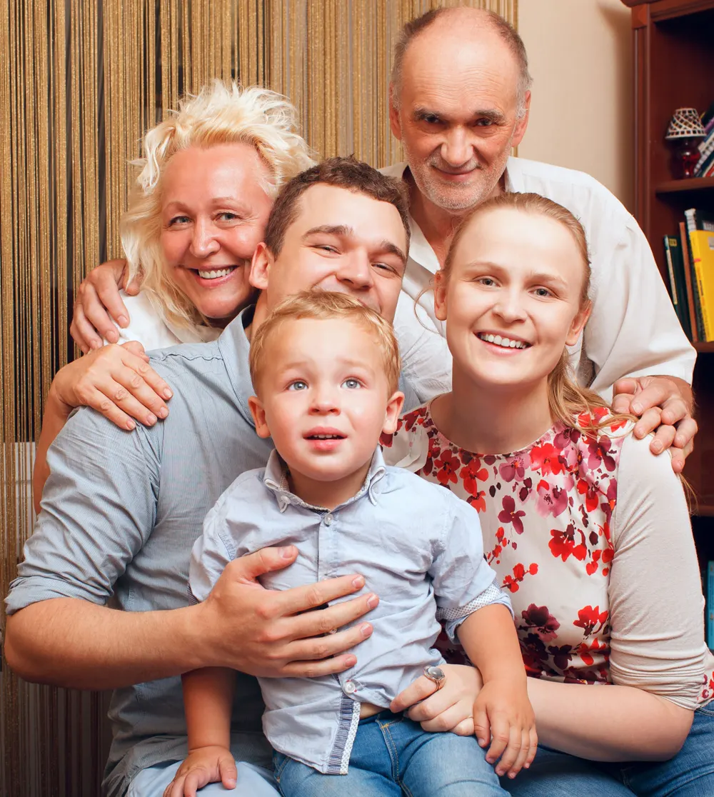 Grandparents, parents and a toddler sharing a hug at home
